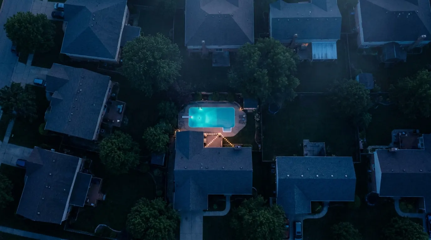 Drone view of a neighborhood at dusk with one lit backyard pool, representing the contractor SEO checklist article